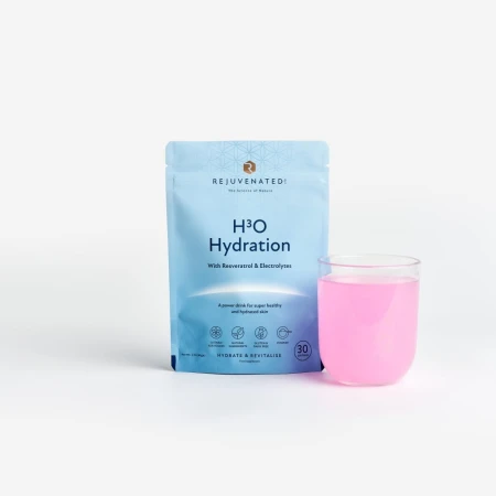 Na białym tle znajduje się niebieska saszetka suplementu Rejuvenated H₃O Hydration z resweratrolem i elektrolitami. Obok opakowania stoi przezroczysta szklanka z różowym napojem przygotowanym z proszku.