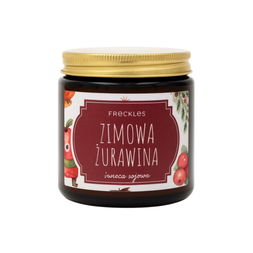 Na zdjęciu znajduje się świeca sojowa marki Freckles o nazwie Zimowa Żurawina. Ma złotą zakrętkę, ciemne szklane opakowanie oraz etykietę z ilustracjami owoców żurawiny i świątecznymi akcentami.