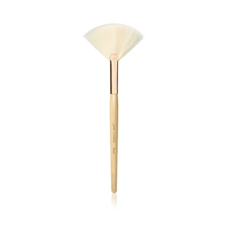 Na zdjęciu znajduje się wachlarzowy pędzel marki Jane Iredale. Jest to lekki, wachlarzowaty pędzel z jasnym włosiem, idealny do: aplikacji rozświetlacza, usuwania nadmiaru pudru, konturowania. Smukły trzonek z naturalnego drewna z złotą skuwką