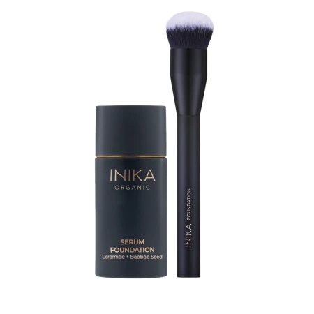 Na zdjęciu widoczny jest kosmetyk marki INIKA Organic – Serum Foundation (podkład serum) z ceramidami i nasionami baobabu. Produkt umieszczono na białym tle, a obok pędzel do płynnych produktów.