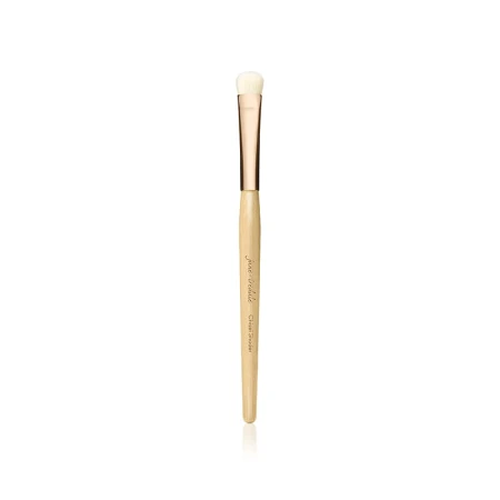 Na zdjęciu widoczny jest pędzel do makijażu marki Jane Iredale. Jest to cienki, precyzyjny pędzel o długim, drewnianym trzonku w naturalnym kolorze, z elegancką, złotą skuwką. Główka pędzla jest mała, zaokrąglona, wykonana z jasnego włosia.