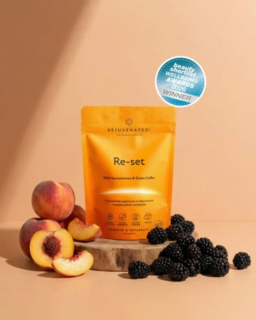 Pomarańczowe opakowanie suplementu Re-set marki Rejuvenated ustawione na drewnianej podstawie, obok brzoskwiń i jeżyn; widoczna informacja o nagrodzie Beauty Shortlist Wellbeing Awards 2026 – Winner.jpg