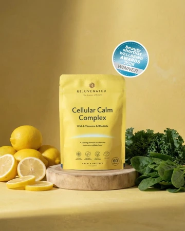 Żółte opakowanie Cellular Calm Complex marki Rejuvenated na żółtym tle. Stoi na drewnianej podstawie, obok cytryny i zielone liście. Widoczna plakietka nagrody Beauty Wellbeing Awards 2026 Winner.jpg