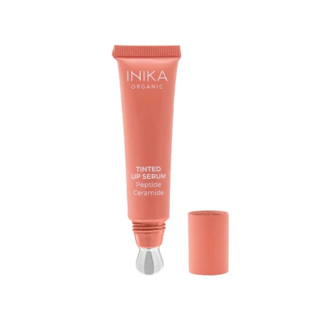 Na zdjęciu widoczna jest tubka INIKA Organic Tinted Lip Serum Peptide Ceramide w koralowym kolorze. Produkt ma metaliczny, chłodzący aplikator oraz odkręconą zakrętkę umieszczoną obok tuby.