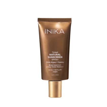 Na zdjęciu jest produkt INIKA Tinted Natural Sunscreen SPF50+ w brązowo-złotej tubie z matowym wykończeniem i złotą zakrętką. Na opakowaniu znajdują się informacje na temat produktu.