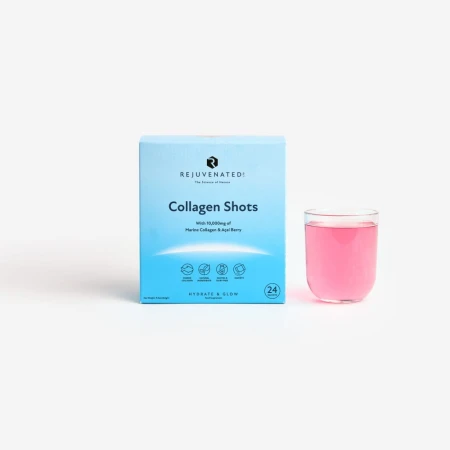Zdjęcie przedstawia stojące, biało-błękitne pudełko suplementu diety w proszku Rejuvenated Collagen Shots. Obok pudełka stoi przezroczysta szklanka wypełniona gotowym, różowym napojem kolagenowym. Tło jest jednolite, jasnoszare.
