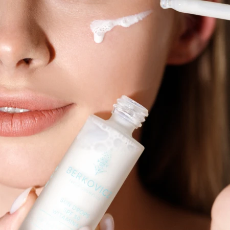Zbliżenie na aplikację produktu Berkovicz Tatra Cosmetics – Sun Drops SPF 50 Witamina C na skórę twarzy. Lekka, mleczna konsystencja nakładana pipetą podkreśla precyzyjną aplikację oraz codzienną ochronę przeciwsłoneczną