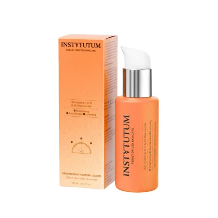 Na zdjęciu znajduje się produkt pielęgnacyjny marki Instytutum Brightening Vitamin C Serum w eleganckiej, pomarańczowej butelce z pompką oraz pomarańczowym kartonikiem.png