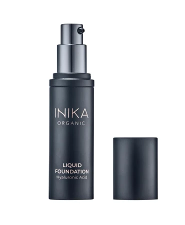 Na zdjęciu widoczny jest podkład INIKA Organic Liquid Foundation z kwasem hialuronowym w eleganckim opakowaniu z pompką, przedstawiony z otwartą zatyczką na jasnym tle, podkreślającym jego minimalistyczny design.
