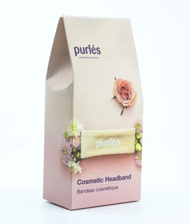 Grafika przedstawia opakowanie kosmetycznej opaski Purlés Cosmetic Headband. Na pudełku widoczna jest beżowa opaska z logo marki, otoczona dekoracyjnymi kwiatami, oraz napis „Cosmetic Headband”.